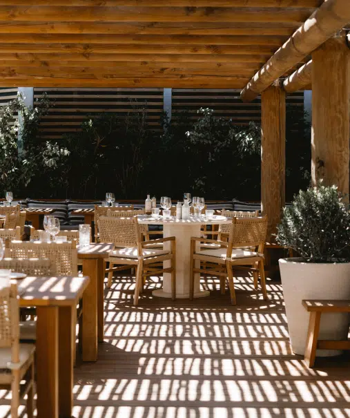 Salle du restaurant plage Pampelonne sous pergola bois, chaises rotin et tables dressées
