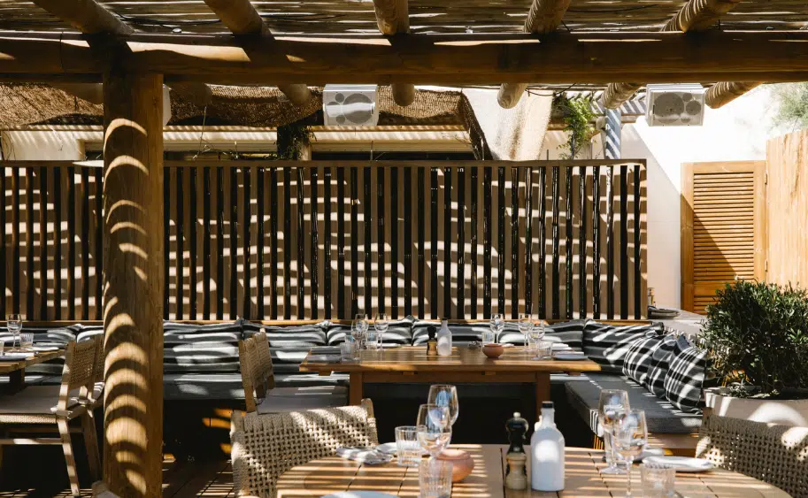 Salle lounge restaurant plage Pampelonne, banquettes ray&eacute;es et pergola en rondins